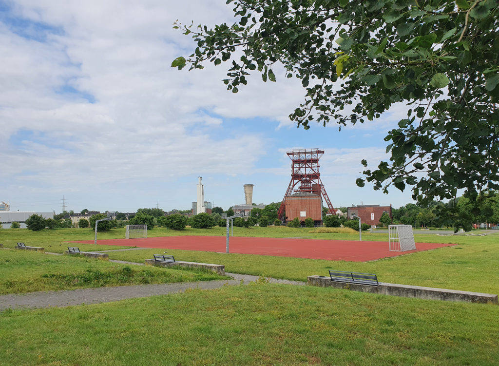 Blick über einen Sportplatz im Consol-Park auf das Fördergerüst der ehemaligen Zeche.